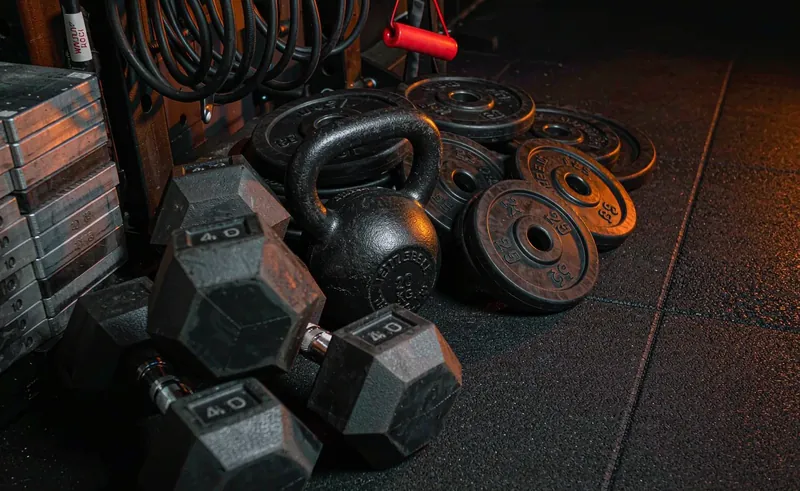 Dumbbells, kettlebell and plates on a dark gym floor