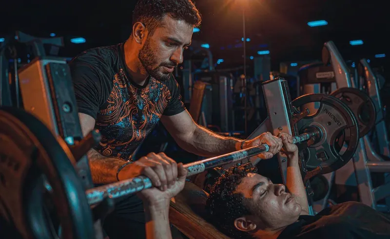 Trainer spotting a client during bench press